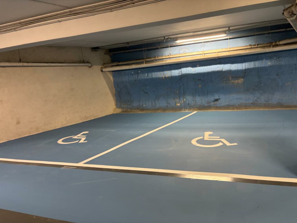 Deux places PMR bleues délimitées dans un parking couvert